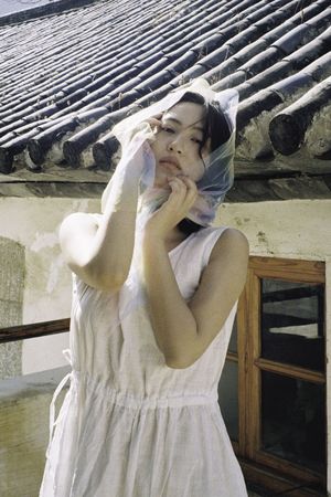 一位年轻女子穿着白色连衣裙 将头靠在脸上