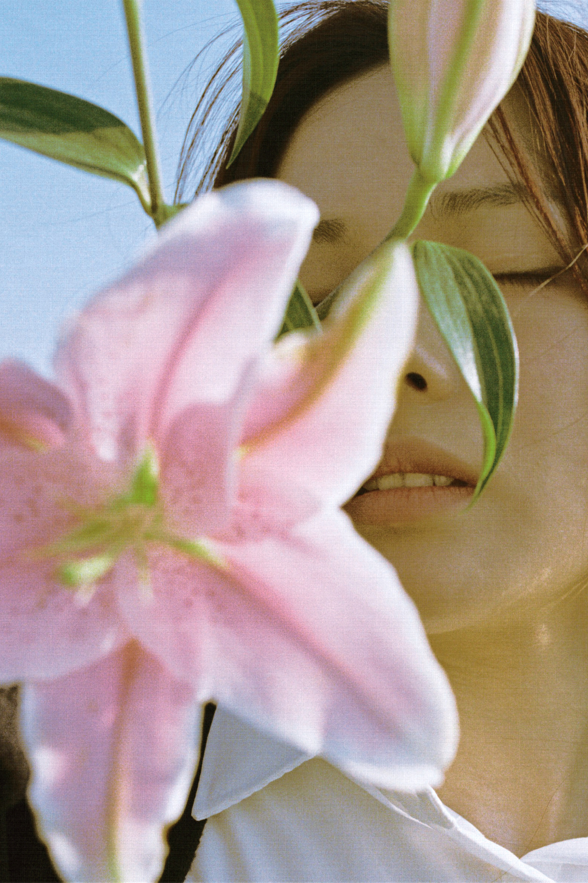 一位年轻女子举着一朵粉色花靠近她的脸