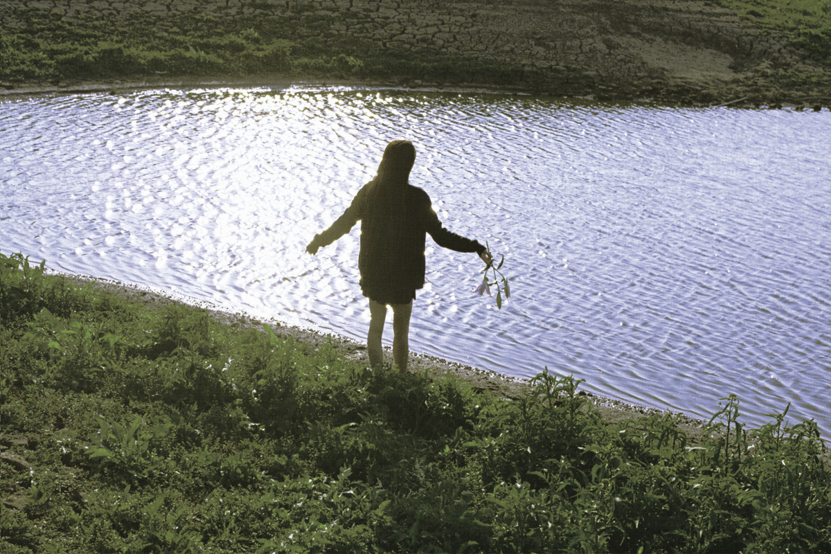 一位女子站在水体或湖泊前面