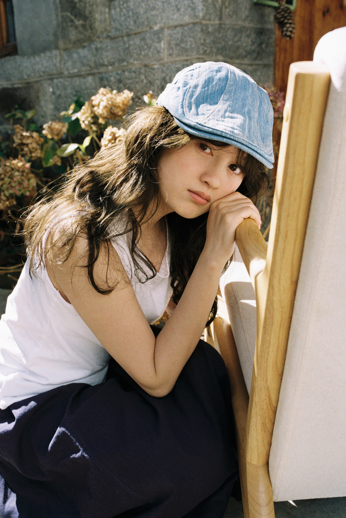 一位年轻女子戴着蓝色帽子坐在白色椅子上