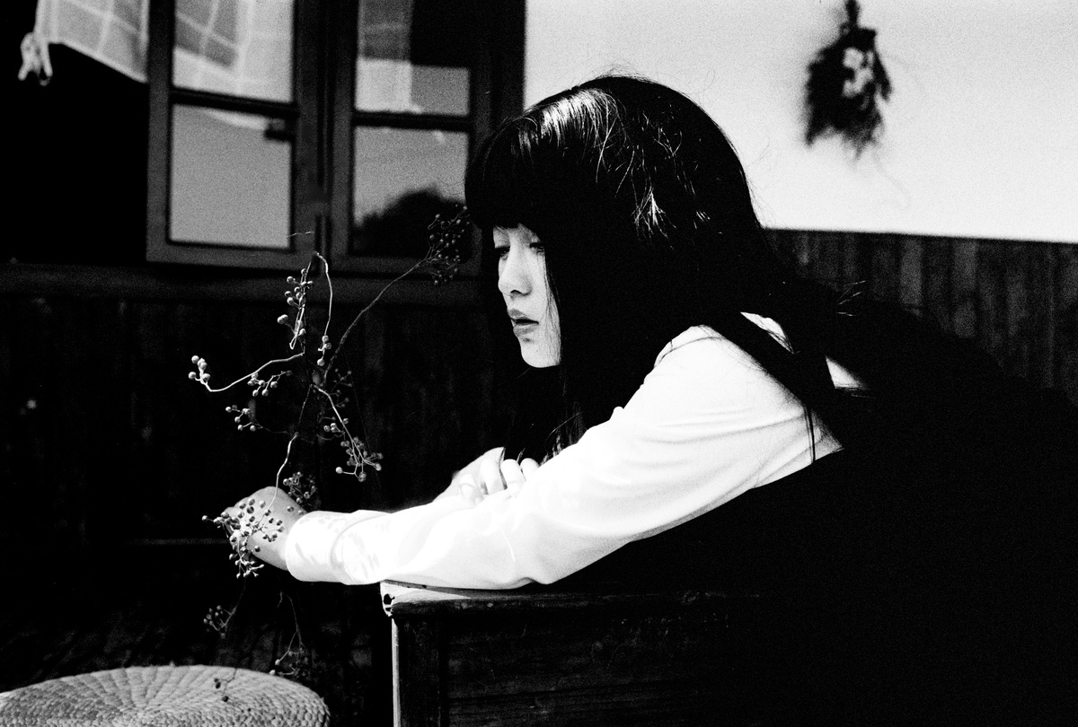 一张黑白照片 一位年轻女子坐在桌子旁 手里拿着一束花