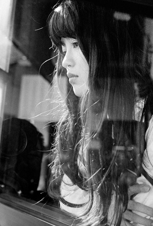 一张黑白照片 一位年轻女子在火车上对着镜子看她的头发。