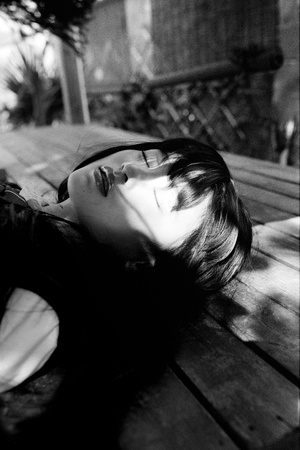 一张黑白照片 一位戴眼镜的年轻女子躺在木凳上