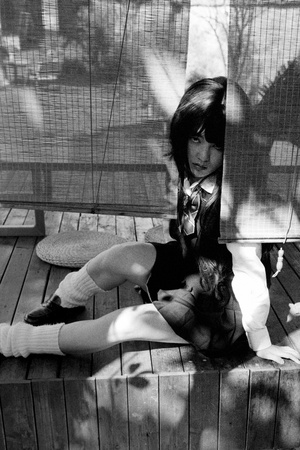 一个黑白照片 一个女人抱着一个小女孩坐在门廊的木凳上