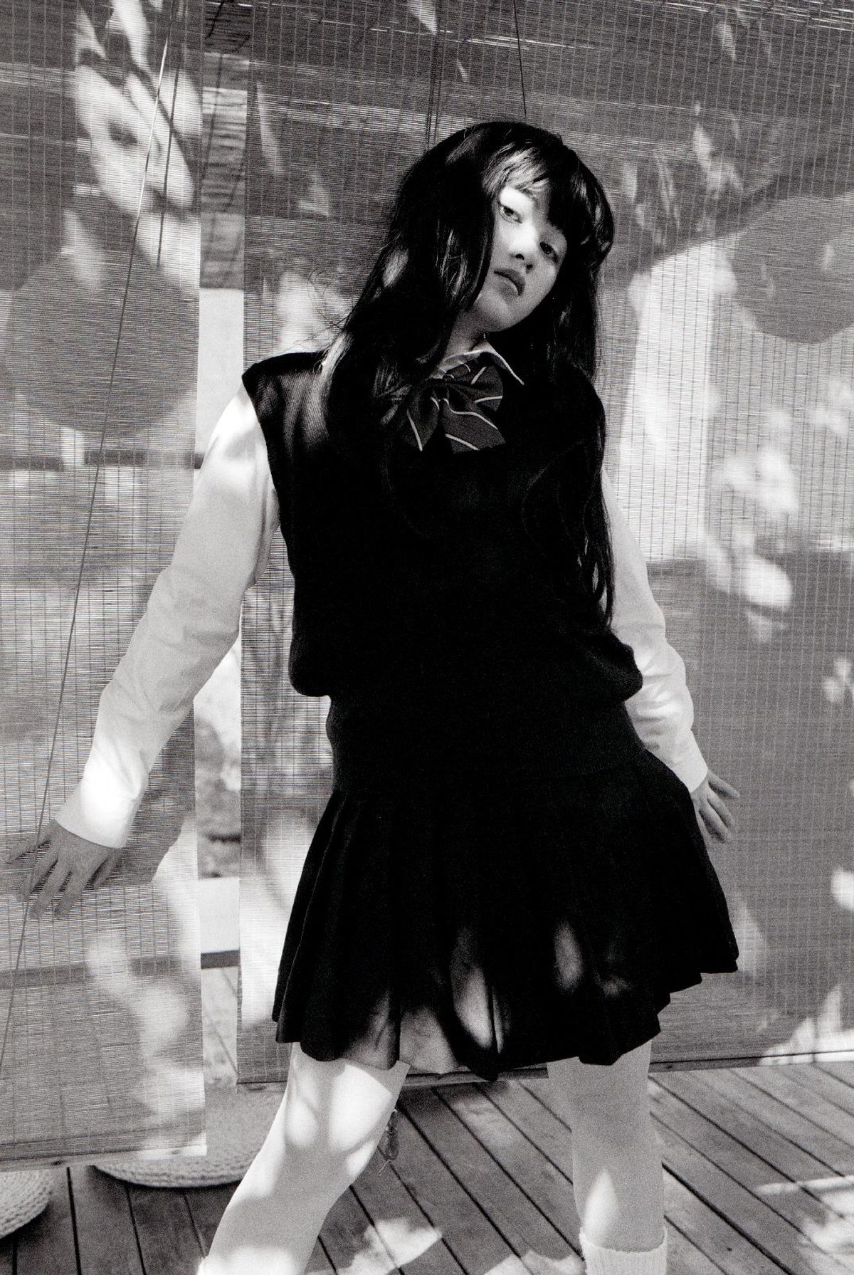 一张黑白照片 一位穿着黑色连衣裙的年轻女子站在一把伞下。