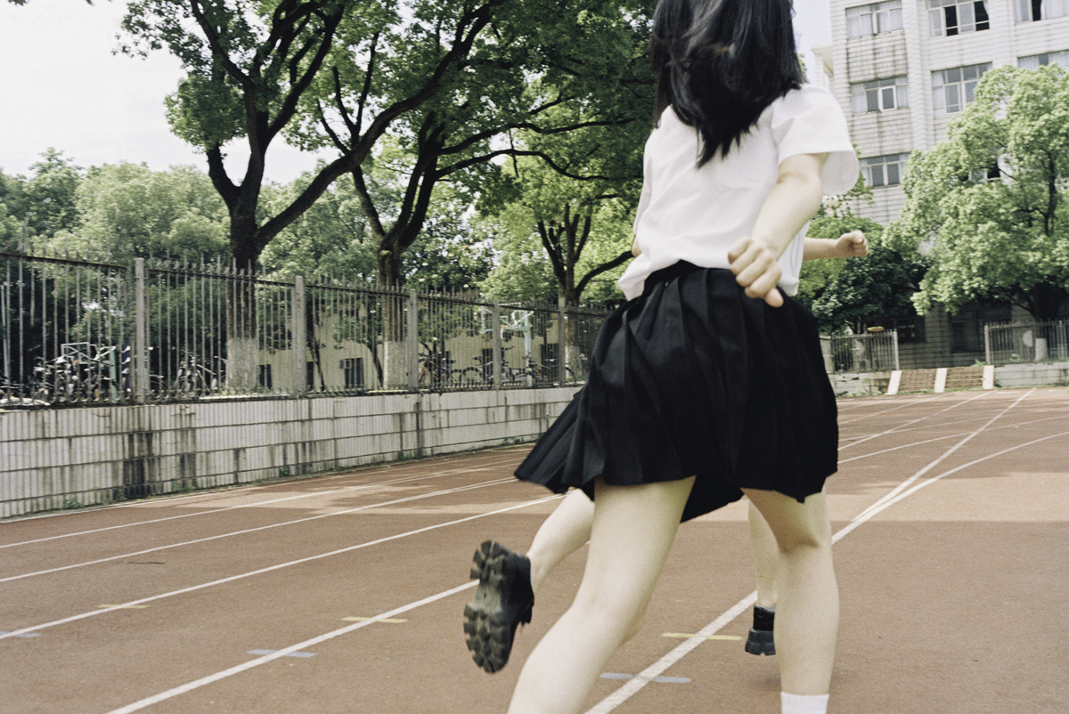 一位穿着黑色裙子的年轻女子在运动场上。