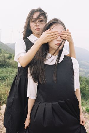两位年轻女子并排站立 互相遮住眼睛