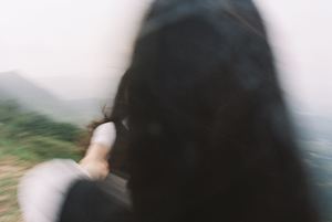 一位黑发女子站在火车上 手里握着一个人的手 背景是山脉。