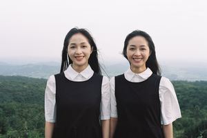 两名穿着黑色衣服的年轻女性在山顶拍照