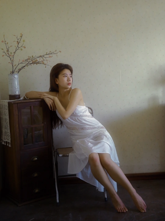 一个穿着白色连衣裙的年轻女子坐在椅子上