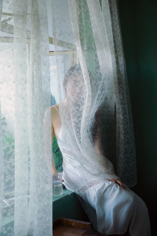 一个戴白色面纱的女人坐在窗户前