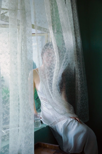 一个戴白色面纱的女人坐在窗户前