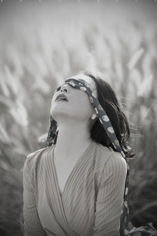 一位年轻女子头戴围巾在田野中的黑白肖像