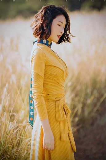 一位穿着黄色裙子的女人站在田野中