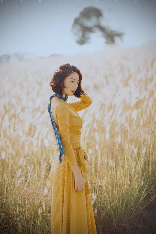 一位穿着黄色裙子的美丽女人站在田野中