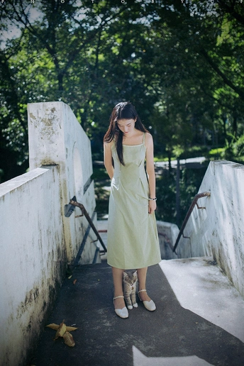 一位穿着绿色连衣裙 手持白色雨伞的年轻女子