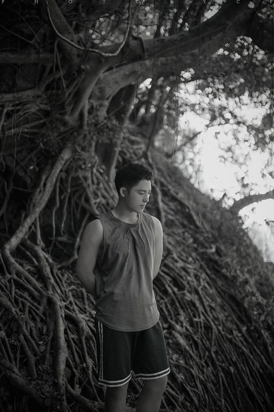 站在河边的一个年轻人正在向上看一棵树根