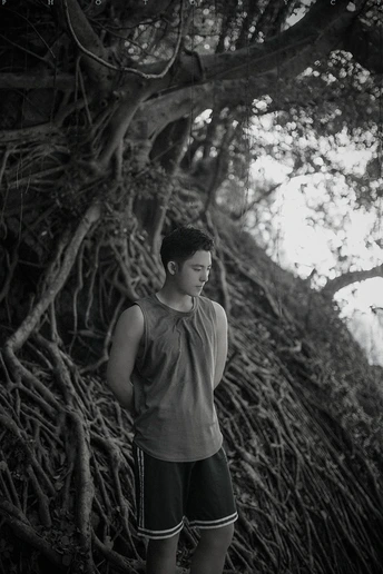 站在河边的一个年轻人正在向上看一棵树根