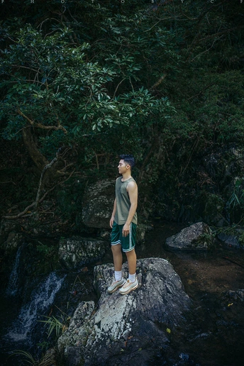 站在森林溪流中的岩石上的年轻男子