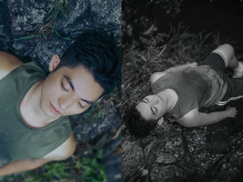 一个年轻男孩躺在森林中的一棵树旁的草地上