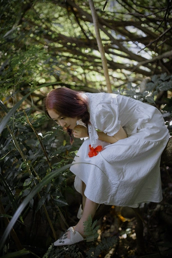 一位穿着白色连衣裙的年轻女子在森林中