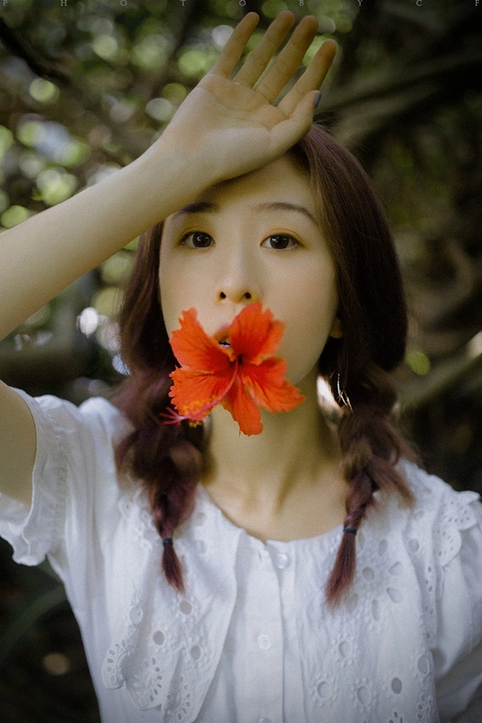 一位穿着白色连衣裙的年轻女子 头戴红花