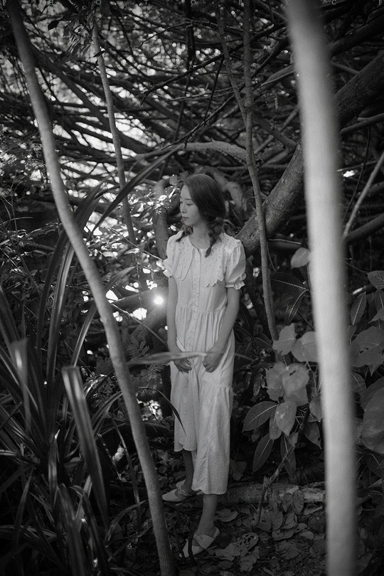 一位穿着白色连衣裙的年轻女子站在森林中 小女孩路过。