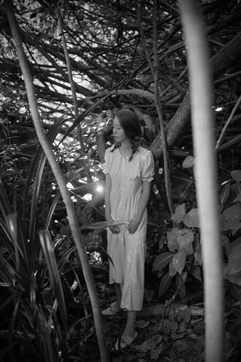 一位穿着白色连衣裙的年轻女子站在森林中 小女孩路过。