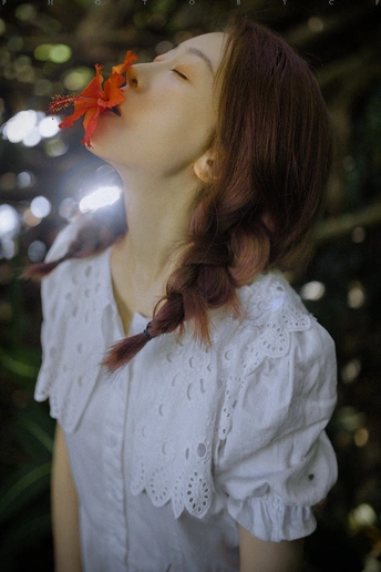 一位穿着白色衬衫 头上有红花的年轻女子