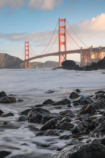 金门大桥日落时分 前景有水域和岩石。