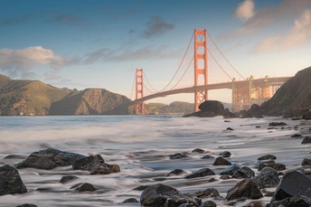 岩石海滩上有岩石和一座跨越水体的桥。