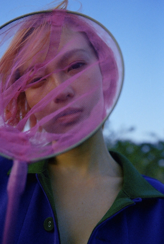 一个戴粉红色头发的年轻女子 用紫色飞盘遮住脸