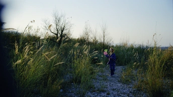 一位妇女和一名儿童走在穿过一片高草地的路径上