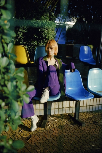 一个小女孩穿着紫色裙子坐在蓝色长凳上