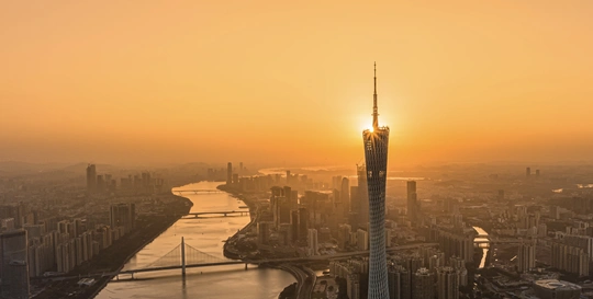 太阳正在落在大城市上 城市中有河流和摩天大楼 位于天际线上。