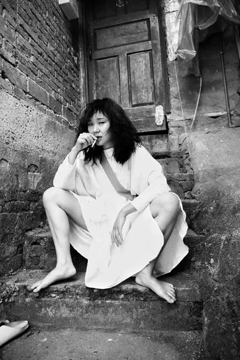 一个穿着连衣裙的年轻女子坐在街边的台阶上
