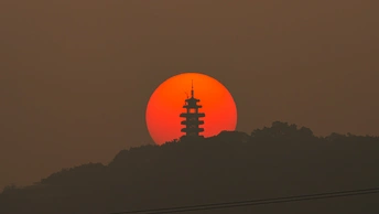 落日余晖映照在一座山丘上的大塔背后