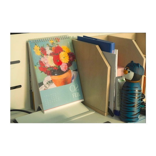 一张桌子的图片 上面有一本书和一个插满花的花瓶。