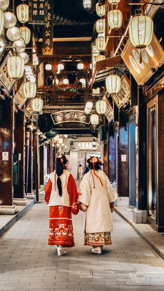 一对穿着传统和服的女性沿着一条狭窄的街道走下来。