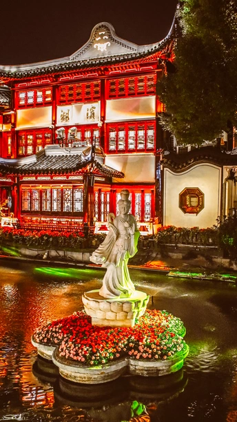 夜晚被红光照亮的城市 水中有一座雕像。