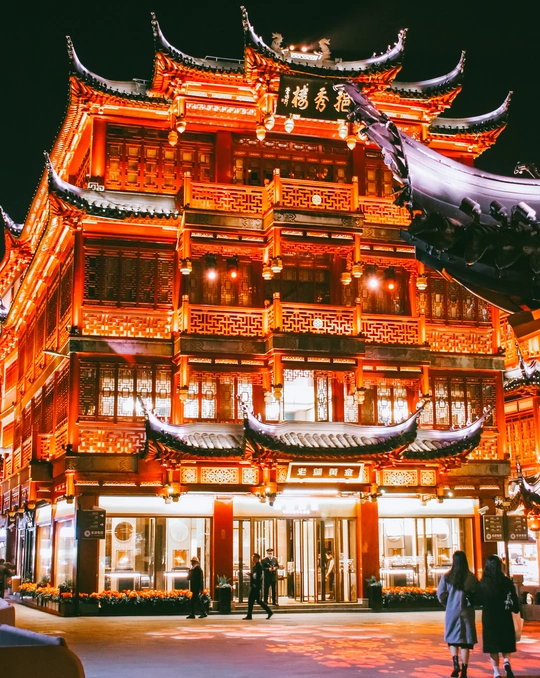 夜晚点亮的寺庙 人们站在建筑前走动。