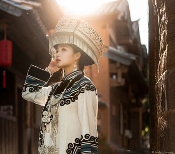 一位穿着传统服装和帽子站在小巷里的年轻女子