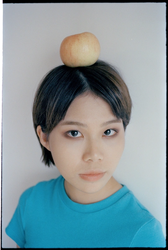 一个头发盘成发髻、头顶有一个苹果的年轻女子