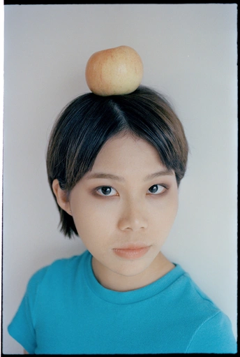 一个头发盘成发髻、头顶有一个苹果的年轻女子