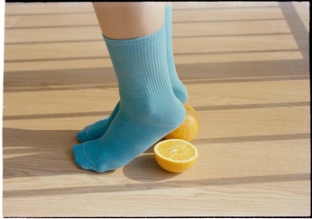 一个人的腿穿着蓝色袜子 坐在地板上 手里拿着柠檬和橙子
