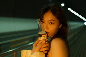 一位年轻女子手里拿着一个瓶子和一个玻璃杯 看着自己的手机