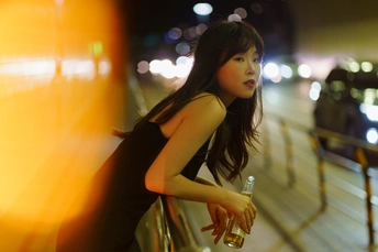 一个拿着瓶子的年轻女人晚上走在街上