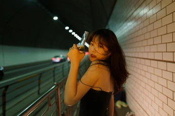 一位身穿黑色连衣裙的年轻女子站在隧道里 手里拿着一杯葡萄酒
