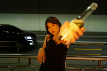 一个穿着黑色连衣裙的年轻女子手里拿着一瓶葡萄酒