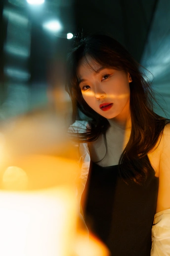 一个穿着黑色连衣裙的年轻女子站在伞下
